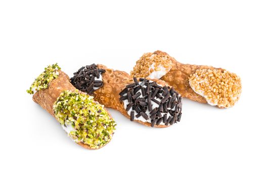 Three cannoli pastries. Traditional Sicilian dessert, filled with a rich ricotta cream enriched with pistachio grain, hazelnut grain and chocolate flakes.