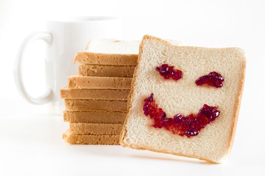 A smile at breakfast, made of strawberry jam, spread on a slice of bread.