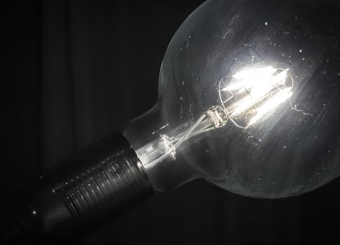 A vintage style glowing lightbulb, illuminate the dark room.