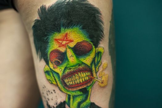 Coloured Tattoo with green face painted in a leg