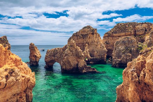 Panoramic view, Ponta da Piedade near Lagos in Algarve, Portugal. Cliff rocks and tourist boat on sea at Ponta da Piedade, Algarve region, Portugal. Ponta da Piedade, Algarve region, Portugal.