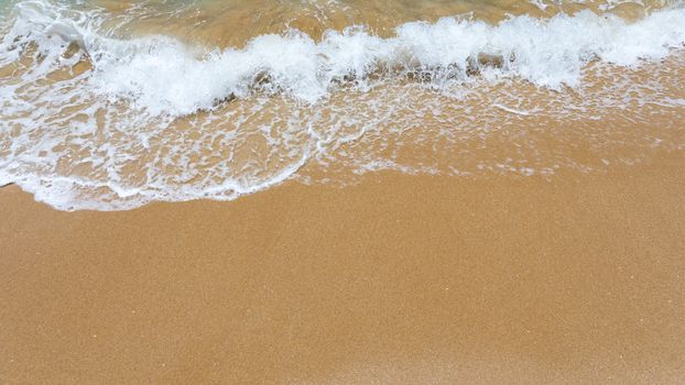 Blue ocean wave on sandy beach. Soft wave of blue ocean on sandy beach. Background. Top view of Beautiful beach with tranquil wave, sea and ocean background, summer vacation concept. 