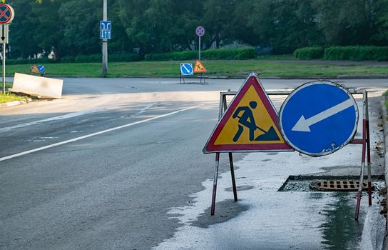 view of several road signs stop, detour, road repairs on a section of road with fresh asphalt