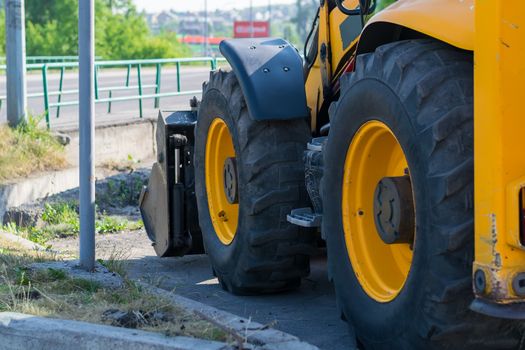 huge tractor wheels, grader on the side of the city street near the road