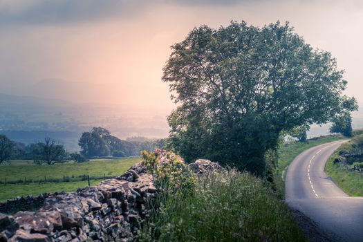 curved road in middle of rural Engalnd with dry stone walls