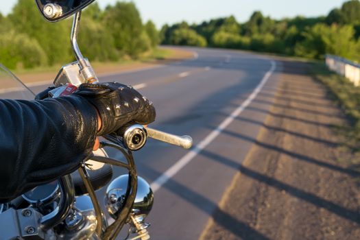 closeup of the hand of the biker on the control handle of the motorcycle and the view of the road