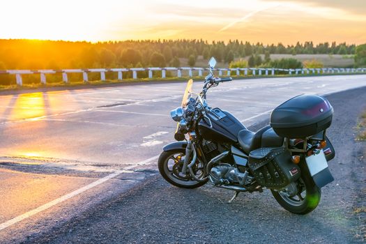 view of a cruise motorcycle on the road against the setting sun