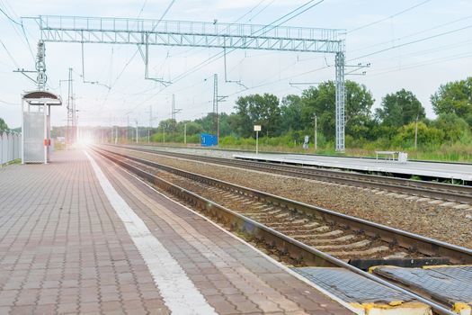 view of the glare of light from the headlights of the approaching train from the platform of the railway station