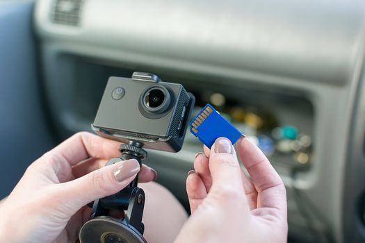 hands of a woman, a car driver, who holds a car DVR, and a memory card to it