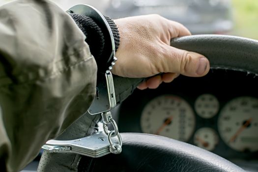 car driver's hand handcuffed to steering wheel, arrest, driving ban by traffic violator