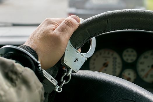 car driver's hand handcuffed to steering wheel, arrest, driving ban by traffic violator