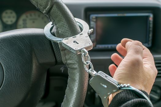 car driver's hand handcuffed to steering wheel, arrest, driving ban by traffic violator