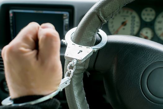 hand of the driver of the car, clenched into a fist, handcuffed to the steering wheel, arrest, prohibition of driving by a traffic violator