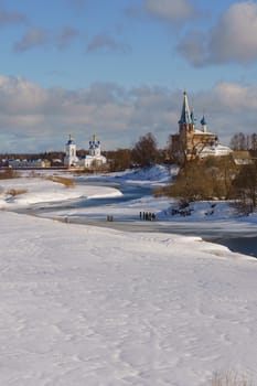 church in a snowy field on a river bank on a clear winter day
