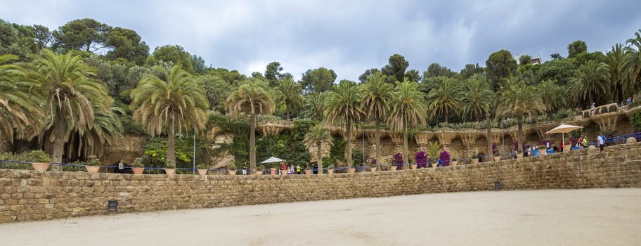 BARCELONA, SPAIN - JULY 3, 2016: Panoramic view of Park Guell. Park Guell is the famous architectural town art designed by Antoni Gaudi, and is popular with tourists.

Barcelona, Spain - July 3, 2016: Panoramic view of Park Guell. Park Guell is the famous architectural town art designed by Antoni Gaudi, and is popular with tourists. People are walking in the park.