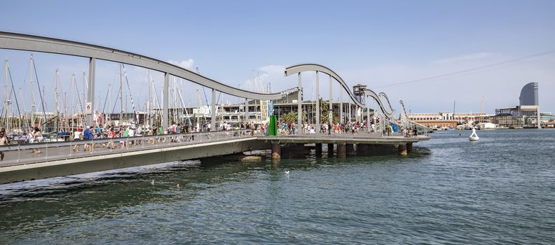 BARCELONA, SPAIN - JULY 4, 2016: Marina Port Vell and the Rambla del Mar in Barcelona. Ramblas del Mar are a wooden bridge built in 1994.

Barcelona, Spain - July 4, 2016: Marina Port Vell and the Rambla del Mar in Barcelona. Ramblas del Mar are a wooden bridge built in 1994. People are walking by bridge.