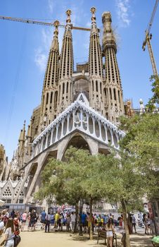 BARCELONA, SPAIN - JULY 5, 2016: La Sagrada Familia - the impressive cathedral designed by Gaudi, which is being build since 19 March 1882 and is not finished yet.

Barcelona, Spain - July 5, 2016: La Sagrada Familia - the impressive cathedral designed by Gaudi, which is being build since 19 March 1882 and is not finished yet. People are resting in the square.