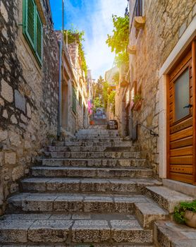 Beautiful street with flowers in the Hvar town, Hvar island, Dalmatia, Croatia. Old Mediterranean street, Hvar town. Old Adriatic town Hvar. Medieval street. Popular touristic destination of Croatia.