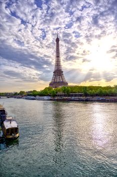 The Eiffel Tower across the Seine River in Paris, France on a sunny day with beautiful clouds.