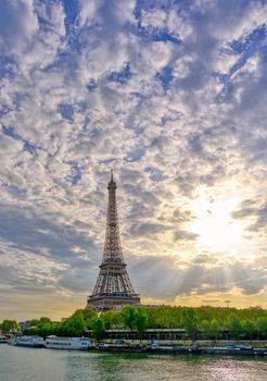 The Eiffel Tower across the Seine River in Paris, France on a sunny day with beautiful clouds.