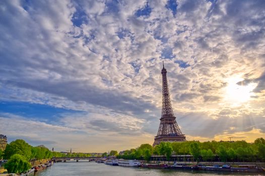 The Eiffel Tower across the Seine River in Paris, France on a sunny day with beautiful clouds.