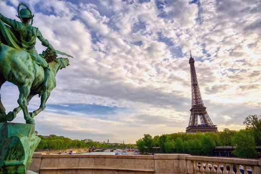 The Eiffel Tower across the Seine River in Paris, France on a sunny day with beautiful clouds.