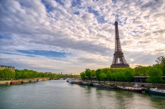 The Eiffel Tower across the Seine River in Paris, France on a sunny day with beautiful clouds.