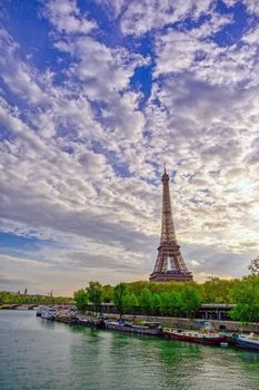 The Eiffel Tower across the Seine River in Paris, France on a sunny day with beautiful clouds.