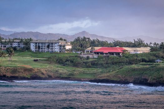 Nawiliwili, Kauai, Hawaii, USA. - January 16, 2020: Early morning light on Timbers Kauai Ocean Golf Club and Residences under blueish clooudscape. White buldings, red roofs and green grass and trees.