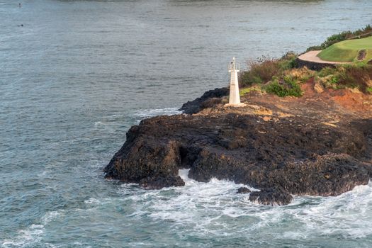 Nawiliwili, Kauai, Hawaii, USA. - January 16, 2020: Early morning light on closeup of Kukii Point lighthouse or beacon on black lava rock peninsula.