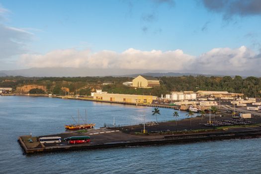 Nawiliwili, Kauai, Hawaii, USA. - January 16, 2020: Early morning light on the docks in the port with Matson container yard and Guardian Self Storage warehouse on hill under light blue cloudscape.