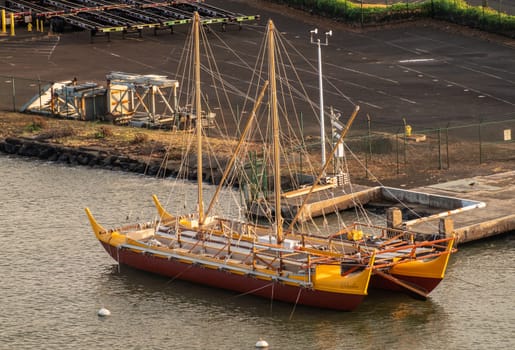 Nawiliwili, Kauai, Hawaii, USA. - January 16, 2020: Early morning light on yellow and maroon Namahoe replica of Pacific Islands Long Distance Canoe upon blue ocean water,