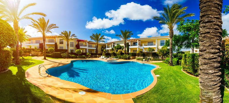 Great backyard with swimming pool, hot tub and lounge chairs. Swimming pool in backyard. Incredible swimming pool and garden with palm trees and flowers in a sunny day.