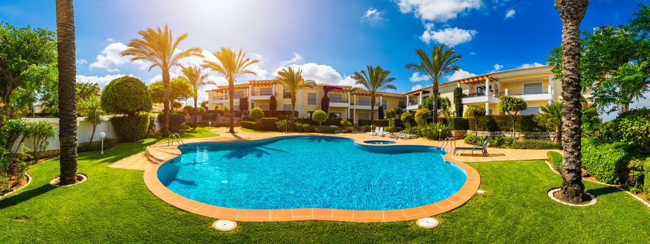 Great backyard with swimming pool, hot tub and lounge chairs. Swimming pool in backyard. Incredible swimming pool and garden with palm trees and flowers in a sunny day.