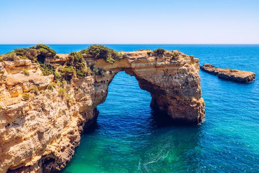 Natural arch above ocean, Arco de Albandeira, Algarve, Portugal. Stone arch at Praia de Albandeira, Lagoa, Algarve, Portugal. View of the natural arch Arco da Albandeira in the Algarve, Portugal. 