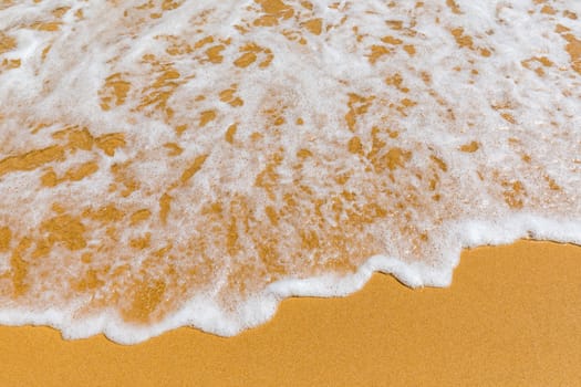 Soft wave of blue ocean on sandy tropical beach. Background of tropical paradise beach with golden sand, travel tourism panorama background concept. Sand and sea waves background.