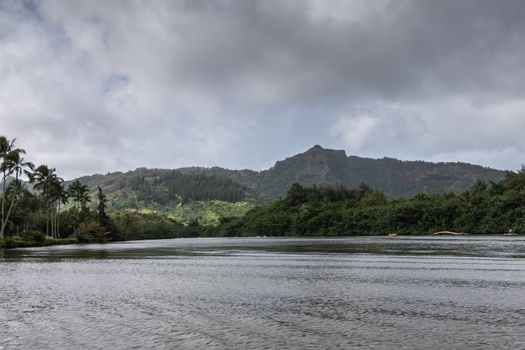 Nawiliwili, Kauai, Hawaii, USA. - January 16, 2020: Wide Gray South Fork Wailua River meanders between green forested hills under gray rainy cloudscape.