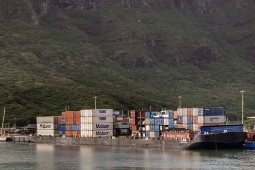 Nawiliwili, Kauai, Hawaii, USA. - January 17, 2020: Closeup of full Haaheo shipping container barge docked in port. Green mountain as backdrop.