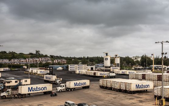 Nawiliwili, Kauai, Hawaii, USA. - January 17, 2020: Matson shipping container yard with plenty loaded trailers under gray rainy cloudscape.