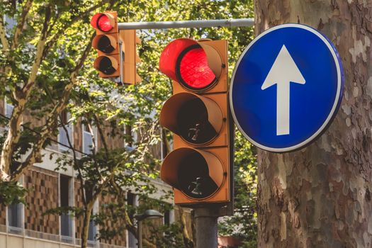 two red semaphore and a blue sign of obligation to go in front