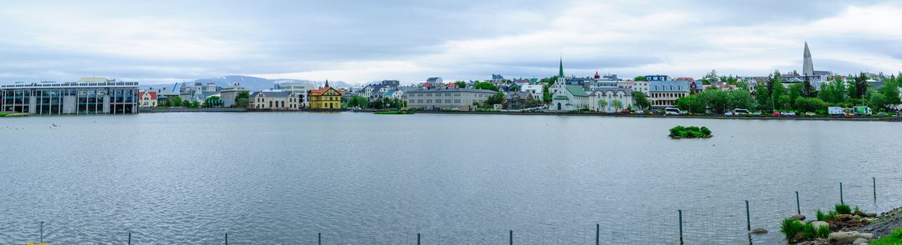REYKJAVIK, ICELAND - JUNE 10, 2016: Panoramic view of the Tjornin (the pond), with various landmarks, locals and visitors, in Reykjavik, Iceland