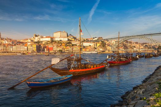 Port wine boats at the waterfront with Dom Luis bridge and the old town on the Douro River in Ribeira in the city centre of Porto in Porugal in Europe. Portugal, Porto