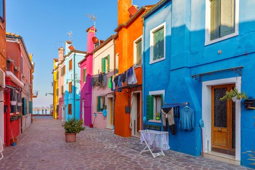 Street with colorful buildings in Burano island, Venice, Italy. Architecture and landmarks of Burano, Venice postcard. Scenic canal and colorful architecture in Burano island near Venice, Italy