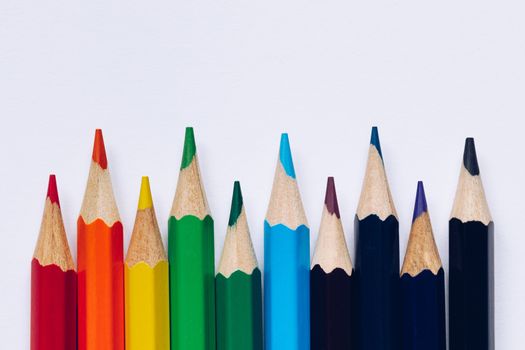Color pencils isolated on white background. Close up of colored rainbow pencils for drawing, concept of preparing for school and discounts on stationery before the school year.