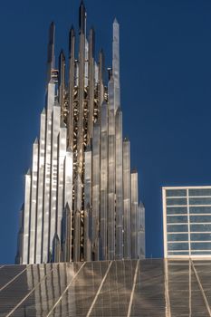 Garden Grove, California, USA - December 13, 2018: Crystal Christ Cathedral. Closeup of Crean Tower against blue sky. Roof of cathedral proper in front.