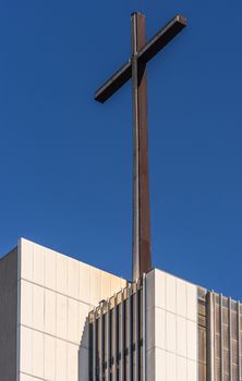 Garden Grove, California, USA - December 13, 2018: Crystal Christ Cathedral. Closeup of cross on top of tower of Hope against blue sky, White stone as base.