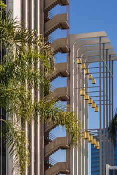 Garden Grove, California, USA - December 13, 2018: Crystal Christ Cathedral. Golden bell composition and part of Tower of Hope against blue sky. Green palm trees.