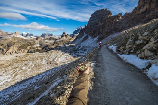 Explorer searching direction with compass in summer mountains, point of view.