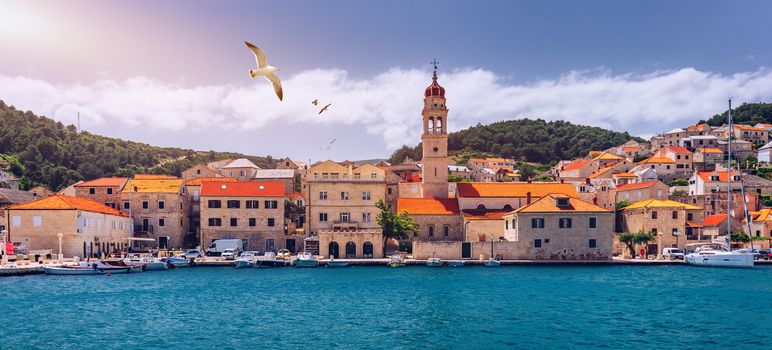 Panorama of picturesque town Pucisca in Croatia, Island Brac, Europe. Pucisca town mediterranean panorama with seagull's flying over the town. Croatia, Island Brac, Europe.