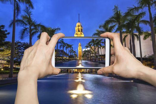 Girl taking pictures on mobile smart phone in Night view Old Clock Tower in Hong Kong